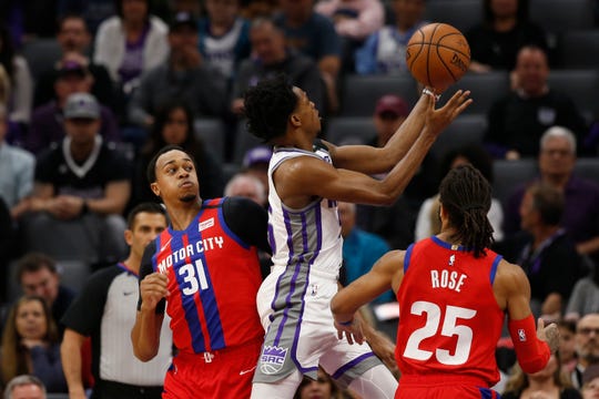 Sacramento Kings guard De'Aaron Fox, center, goes to the basket between Detroit Pistons' John Henson, left, and Derrick Rose, right, during the first half.