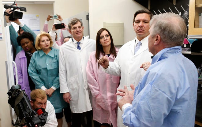 From left, Deputy Secretary for Health Dr. Shamarial Roberson, State Senator State Senator Janet Cruz, State Surgeon General Dr. Scott Rivkees, Lieutenant Governor Jeanette Nuñez, Governor Ron DeSantis, looks on while Andrew Cannons, Laboratory Director at the Bureau of Public Health Laboratories explains the testing procedures of potential coronavirus cases at the Florida Department of Health Laboratory in Tampa, Florida on Monday, March 2, 2020.
