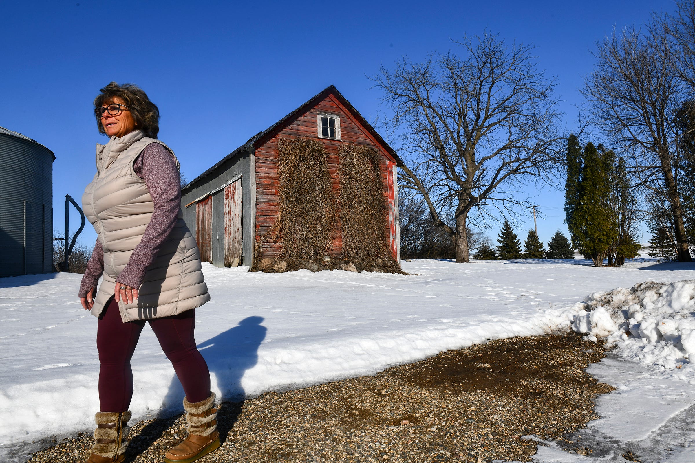 Barb Ruhland walks between buildings Wednesday, Feb. 5, 2020, on her farm near Watkins, Minn.