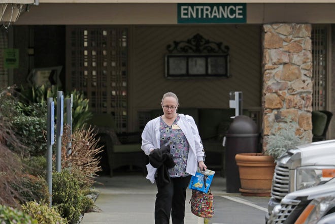 A nurse walks away from the entrance to the Life Care Center in Kirkland, Washington, near Seattle, on Tuesday, March 3, 2020. The facility has been linked to several confirmed cases of COVID-19 coronavirus.