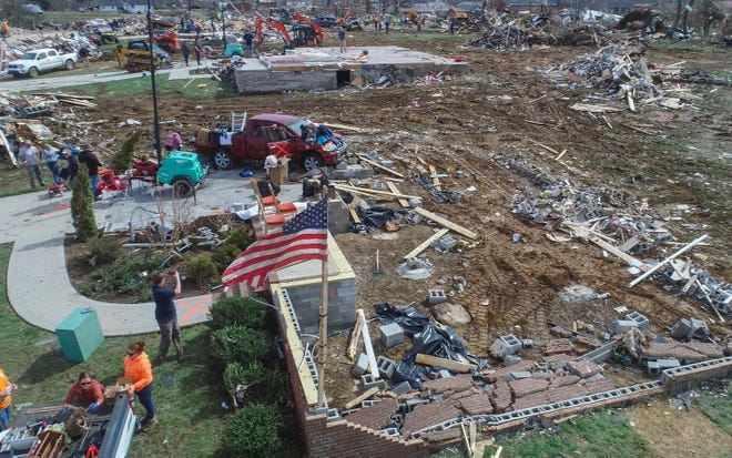 An American flag flies high over the rubble left by a tornado Tuesday morning.