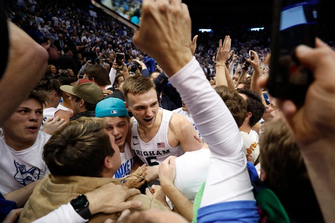Brigham Young Cougars guard Jake Toolson (5) is mobbed by fans after their upset over the Gonzaga Bulldogs at Marriott Center.
