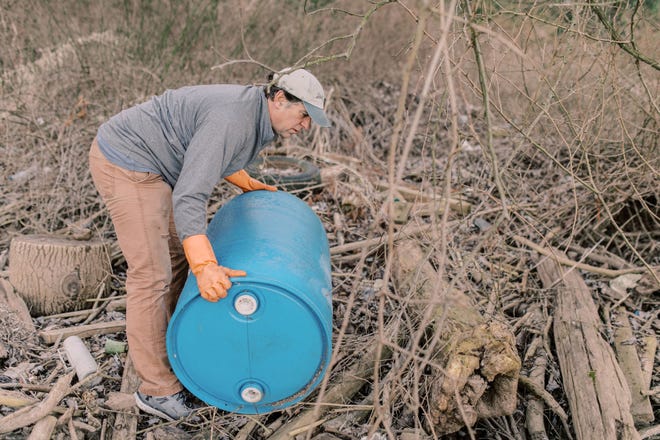 John Naylor picks up a plastic container from the banks of the Susquehanna River near Wrightsville, Pa.