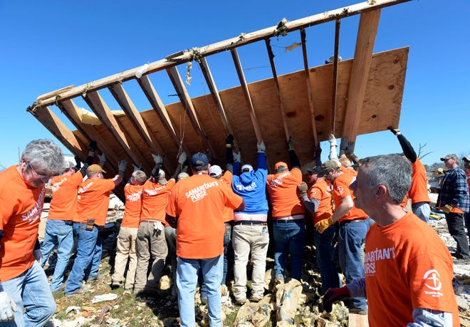 Samaritan Purse volunteers lift a section of the side wall of a tornado destroyed house while cleaning up an area around the house on Saturday March 7, 2020, in Cookeville, Tenn.