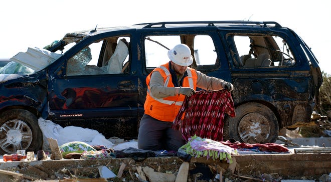 Lee company worker Tucker Gill carefully folds the clothes of the victims of the tornado after gathering the items around a destroyed house on Saturday March 7, 2020 in Cookeville, Tenn. 