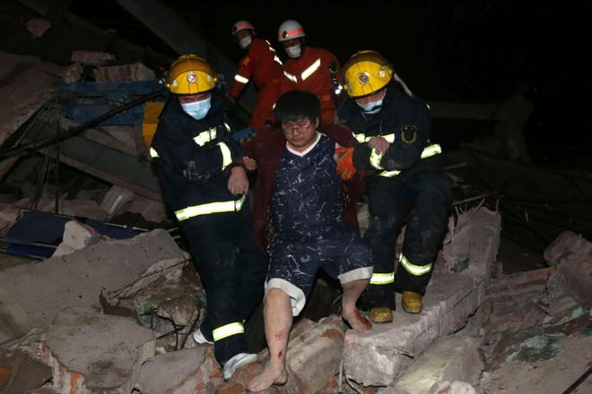 Rescuers help a man from the rubble of a collapsed hotel building in the city of Quanzhou, in southeast China's Fujian province Saturday, March 7, 2020. The hotel used for medical observation of people who have Contact with coronavirus patients collapsed in southeast China on Saturday, trapping dozens, state media reported.
