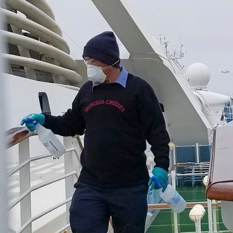 A cruise ship worker cleans a railing on the Grand