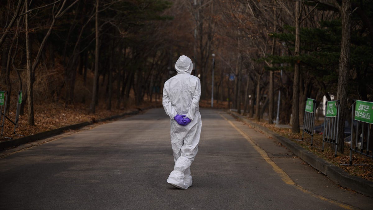 A health worker wearing a protective suit waits at a drive-through testing centre for the COVID-19 coronavirus in Seoul on March 7, 2020.  South Korea has the biggest number of COVID-19 coronavirus cases outside China.
