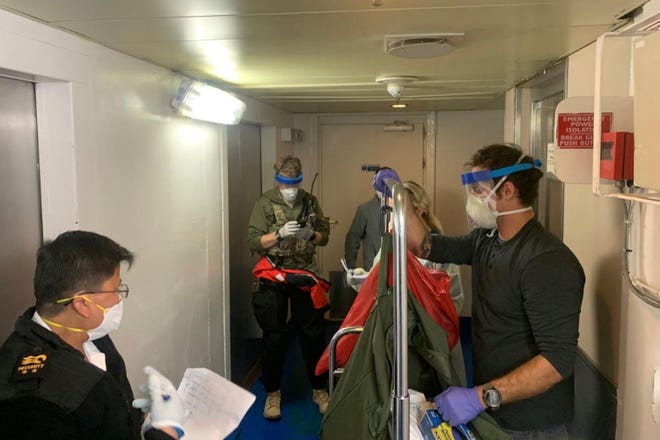 In this Thursday March 5, 2020, a photo, published by the California National Guard, Guardian Angels, a group of medical personnel with the 129th Rescue Wing, working alongside individuals from the Centers for Disease Control and Prevention, puts on equipment protection after transmitting virus test kits for the Grand Princess cruise ship off the coast of California.