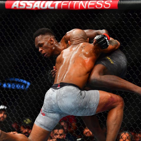 Israel Adesanya (red gloves) fights Yoel Romero (b