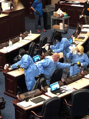 Cary Pigman, an ER doctor, helps House cleaning staff sanitize desks after five legislators and a staffer self-isolated because of possible exposure to coronavirus.