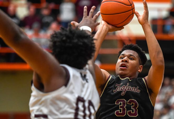 Webster County's Destin Allen (33) shoots a jump shot over Madisonville's Ksuan Casey (00) as the Webster County Trojans play the Madisonville Maroons in the Second Region boys championship Tuesday evening at Hopkinsville High School, March 9, 2020.