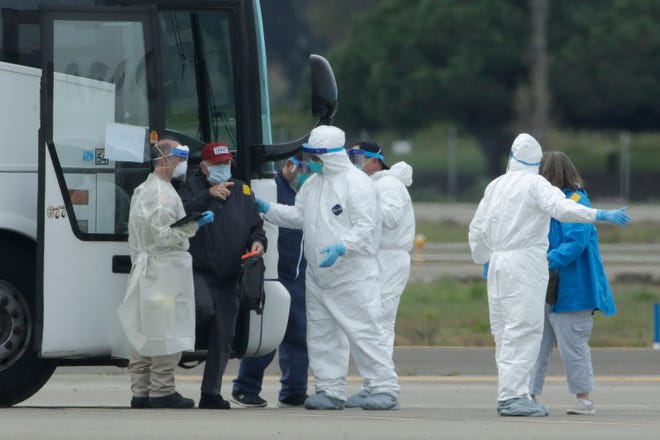 Passengers from the Grand Princess, a cruise ship carrying multiple people who have tested positive for COVID-19, exit a bus before boarding a chartered plane in Oakland, Calif., Tuesday, March 10, 2020. The passengers on the flight are going to San Antonio to be quarantined at Lackland Air Force Base. (AP Photo/Jeff Chiu)