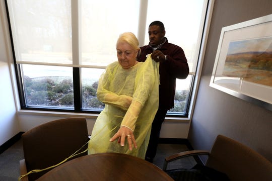 Johanna Mannone, 79,  gets help from Donald Tolliver, the executive director of WellBridge of Rochester Hills, putting her gown on before seeing her husband, Mike, on Friday for a onetime, specially arranged visit.