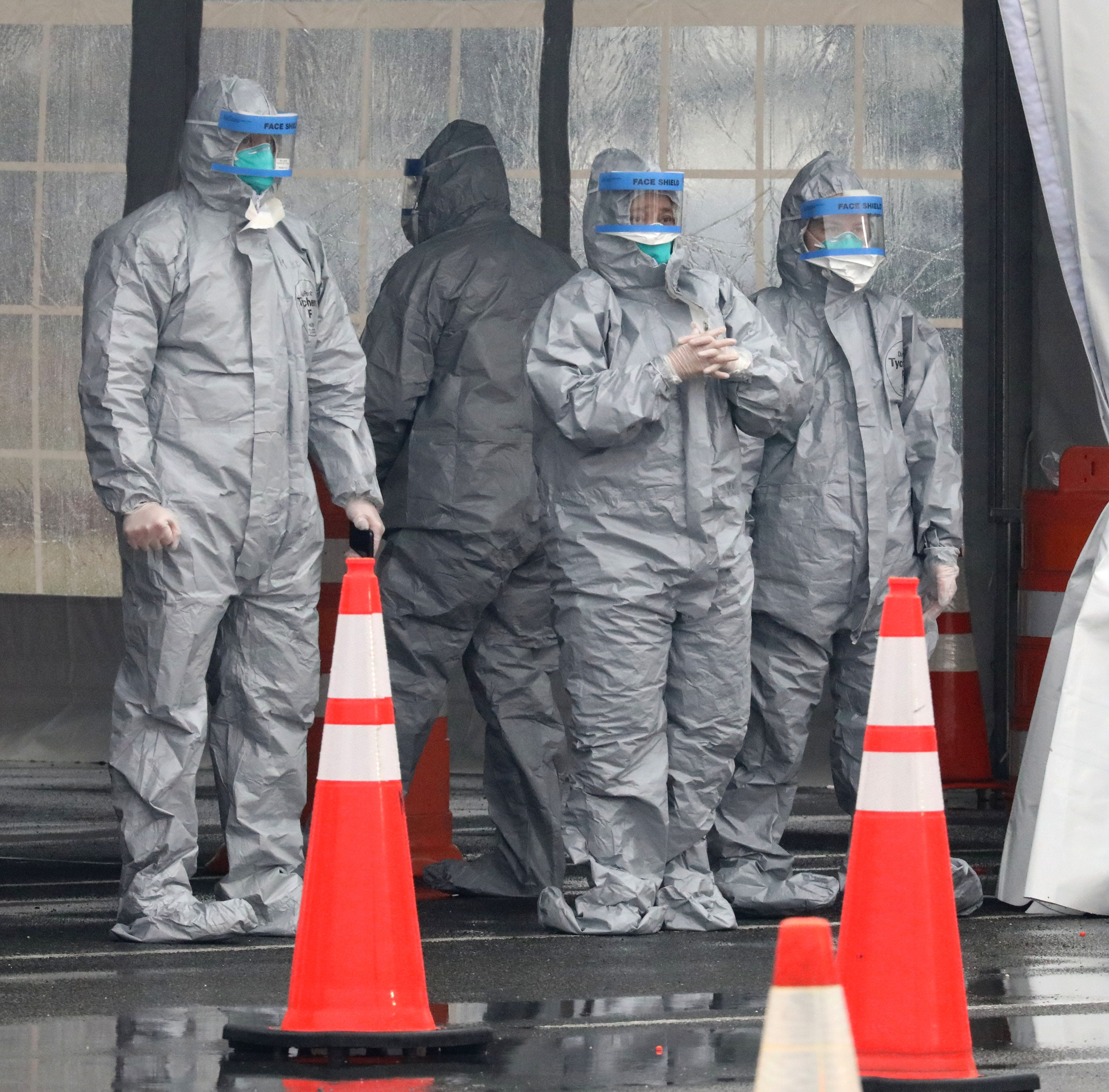 Workers in protective clothing wait for cars to arrive at Glen Island Park in New Rochelle, as New York State's first drive through COVID-19 mobile testing center opens, March 13, 2020.