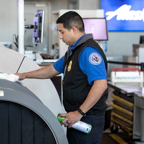 A TSA screening officer uses Lysol disinfecting sp
