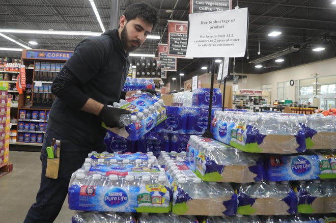 Ferndale Foods employee Fanar Alsaegh stocks water one of the items selling fast due to panic buying caused by the Coronavirus Pandemic Saturday, March 14, 2020.