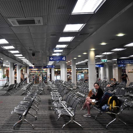 People sit in a near-empty departure lounge, amid concerns over the spread of the COVID-19 coronavirus, at Chiang Mai International Airport on March 15, 2020.
