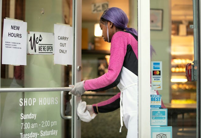Timeka Smith said she's a little nervous, but trying not to panic as she works the counter at Hultman's Donuts in Over-the-Rhine. She said she's wearing gloves and continually cleaning counters, doorknobs and other things, Tuesday, March 17, 2020.