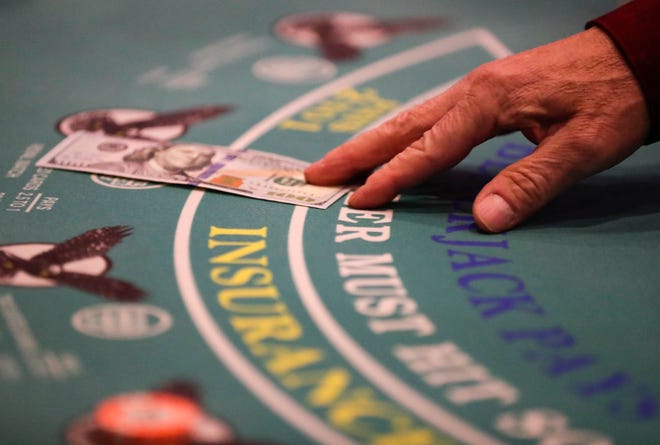 FILE - A man grabs a $100 bill during a blackjack game March 17, 2020, at Oneida Casino in Green Bay.