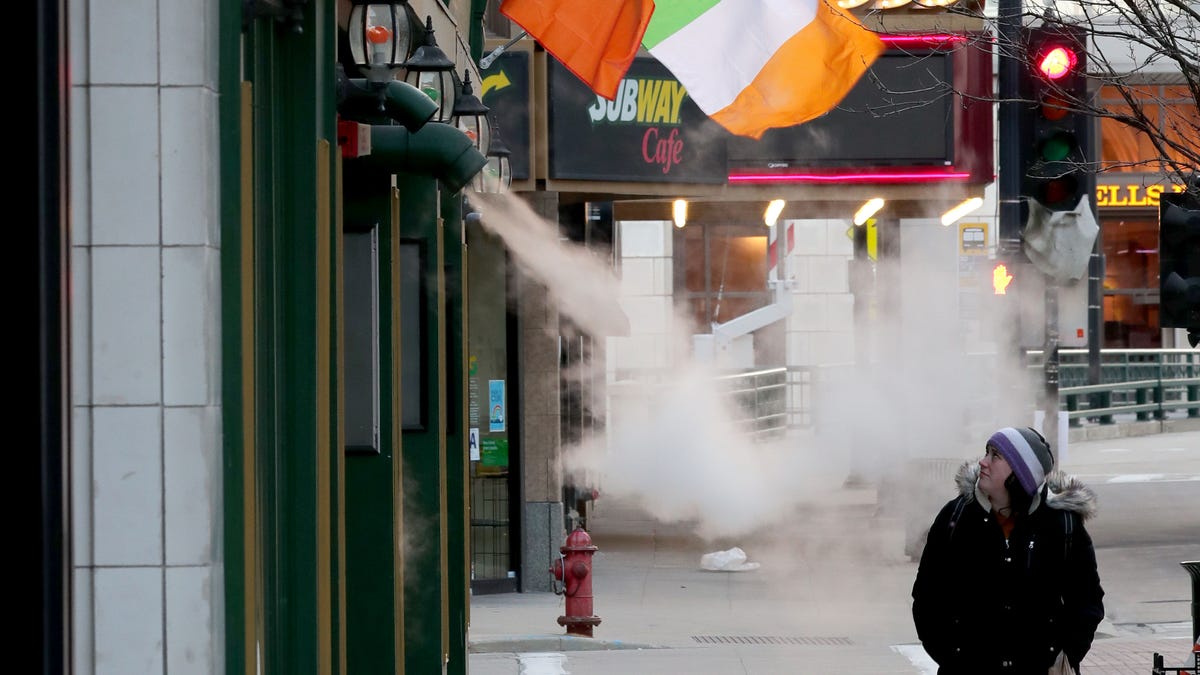 Katie Simpson, walks past a closed Mo's Irish Pub on W. Wisconsin Avenue on St. Patrick's Day in Milwaukee on Tuesday, March 17, 2020. It's a St. Patrick's Day that was shut down by the coronavirus as Milwaukee and 10 other Milwaukee County municipalities ordered bars and restaurants to close effective 2:01 a.m. Tuesday, except for carryout, delivery and curbside service — an effort of elected and health officials to head off a growing   number of coronavirus cases.