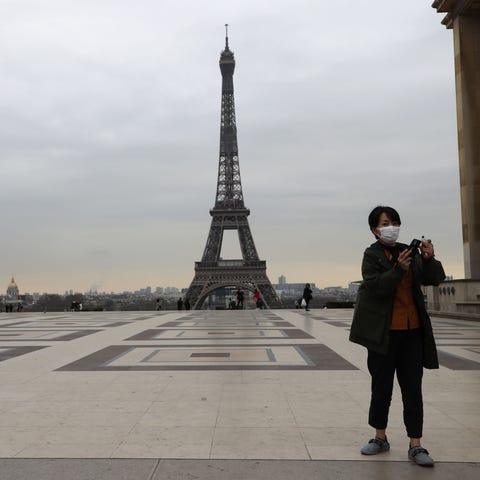 A tourist wearing a protective facemask takes a pi