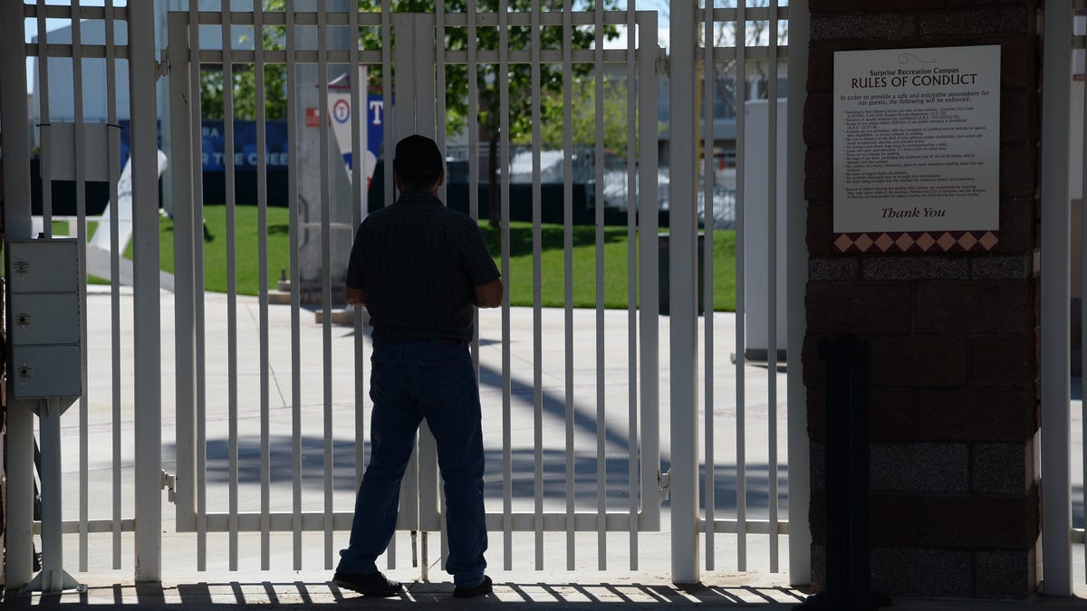A fan stands outside of the gates at Surprise Stadium.