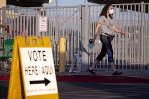 A woman walks with her ballot to vote in the Democratic presidential primary on March 17, 2020, at the Madison Park School polling location in Phoenix.