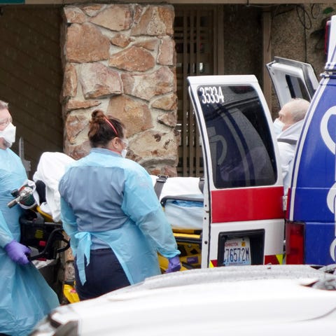 Medical workers load a sick patient into the back 