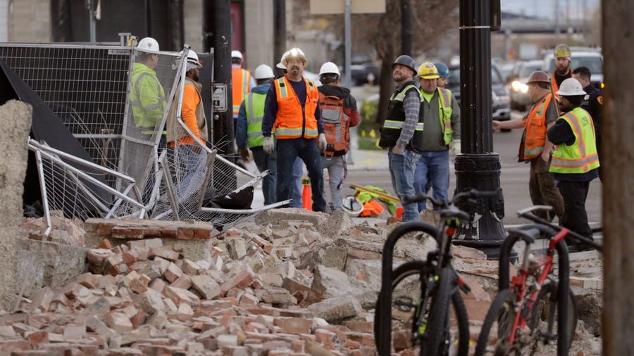 Construction workers look at the rubble from a building after an earthquake Wednesday, March 18, 2020, in Salt Lake City.  A 5.7-magnitude earthquake has shaken the city and many of its suburbs. The quake sent panicked residents running to the streets, knocked out power to tens of thousands of homes and closed the city's airport and its light rail system.