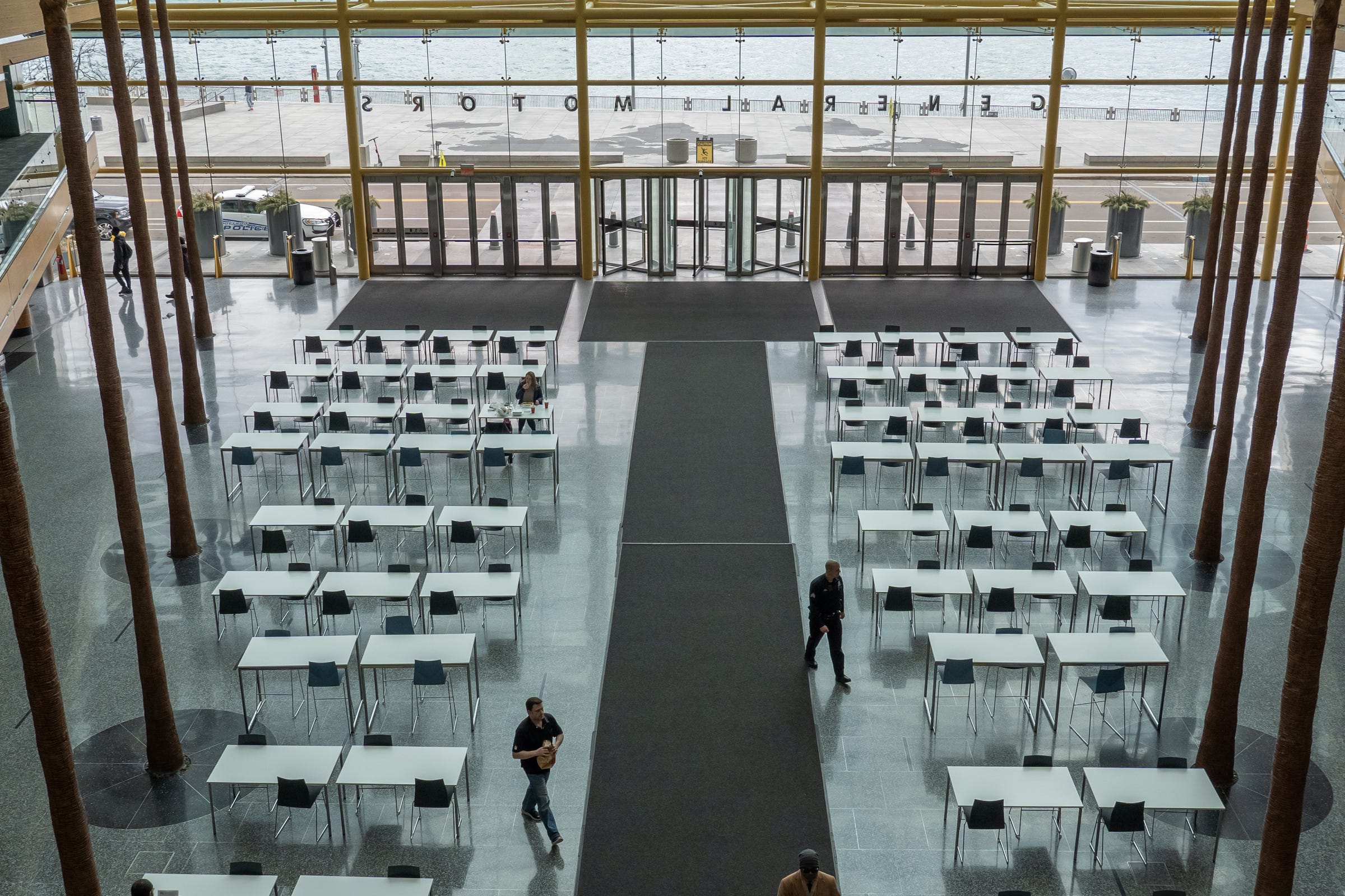 A few people mill around the General Motors' Wintergarden at the Renaissance Center in downtown Detroit on Tuesday, March 17, 2020.