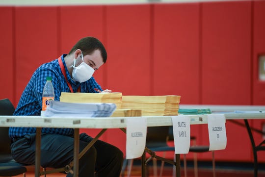 North College Hill High School Math teacher, Jason Gregory, 33, grades papers as he waits for students to come pick up their packets so they can continue their schooling form home during the COVID-19 pandemic.