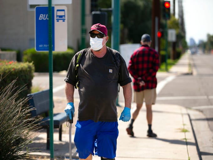 Denver Gilbreth of Phoenix, who has underlying respiratory issues, walks along East Thomas Road in from his Phoenix apartment to a nearby pharmacy in Phoenix to pick up his medication on March 20, 2020. Gilbreth is wearing a mask and gloves every time he leaves his apartment because of his concerns of contracting the coronavirus with his underlying conditions. 