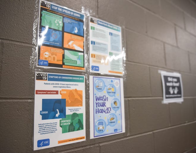 Posters listing the symptoms of the coronavirus are posted on the wall on Thursday, March 19, 2020 at the Bishop Dudley Hospitality House in Sioux Falls.