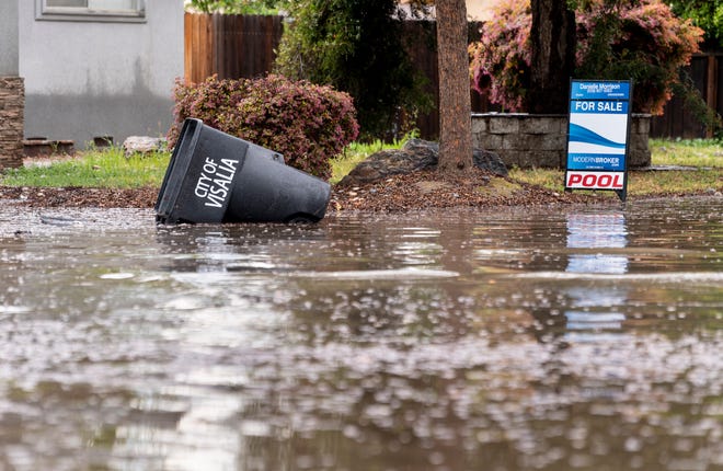Water from the submerged intersection of Tulare Avenue and Sowell street overflowed curbs after the rain in Visalia on Thursday, March 19, 2020.