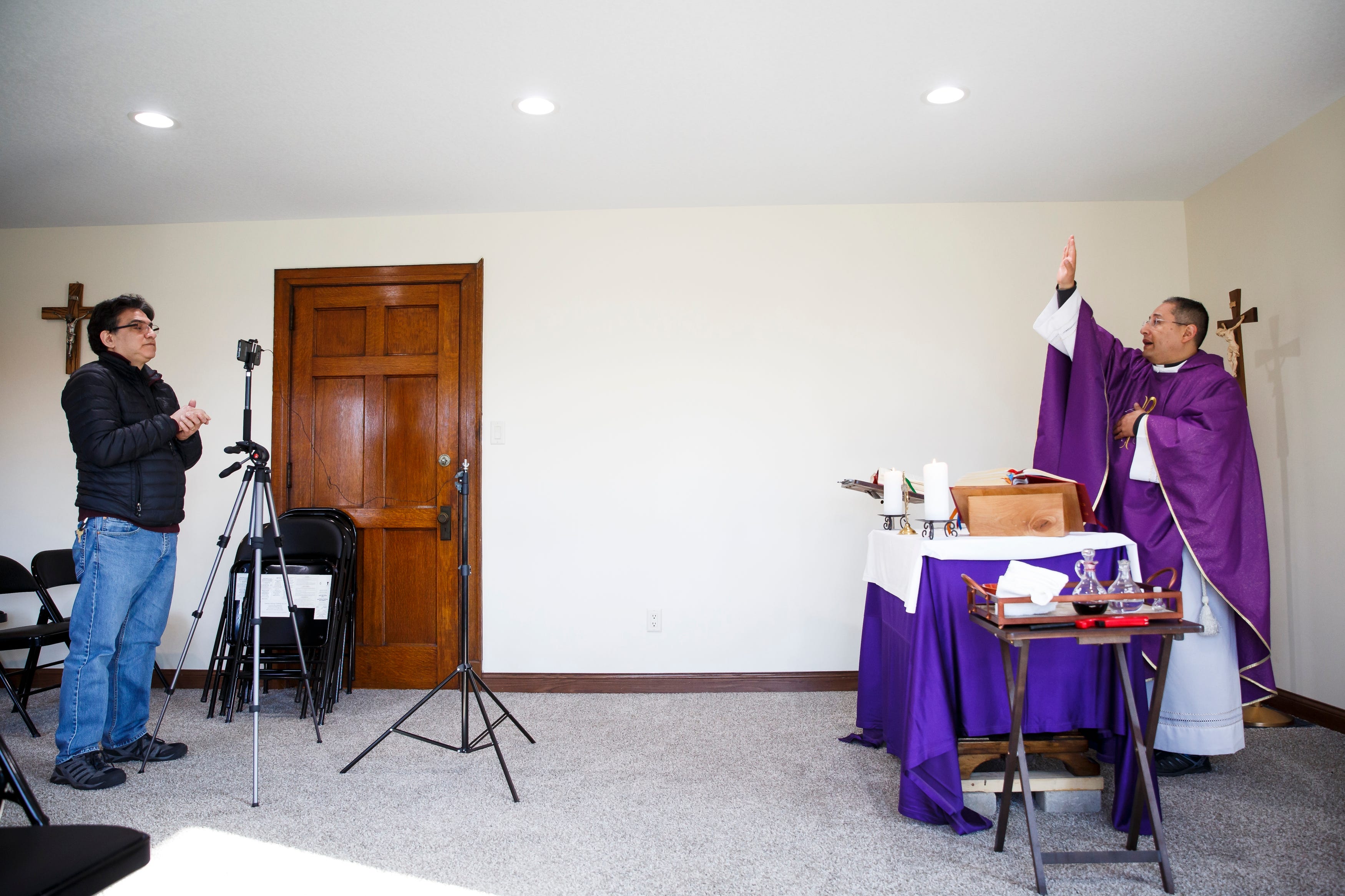 Wilfrido Matamoros streams a church service led by the Rev. Fabian Moncada in a makeshift chapel at Our Lady of the Americas Church on Saturday, March 21, 2020, in Des Moines. The church has stopped doing in-person services; instead, they have moved them into this chapel and only allow one or two parishioners to attend in person.