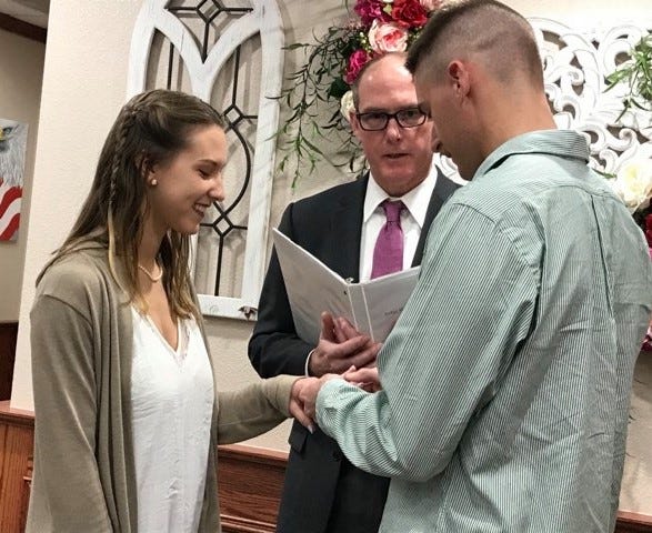 Wichita County Justice of the Peace Robert Woodruff looks on as William Payne slips a ring on the finger of his bride, Savannah Pollard, on March 20, 2020. They didn't imagine they would get married during a time like this, but all that matters to them is starting their lives together.
