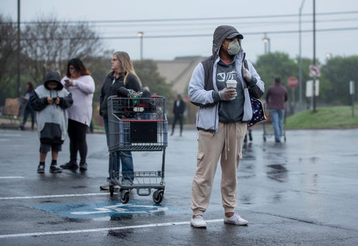 Shakaira Brooks and scores of other people wait in line with appropriate social distancing for the 8 a.m. opening of the H-E-B in the Tanglewood Village Shopping Center in South Austin on Sunday March 22, 2020, amid the coronavirus pandemic.