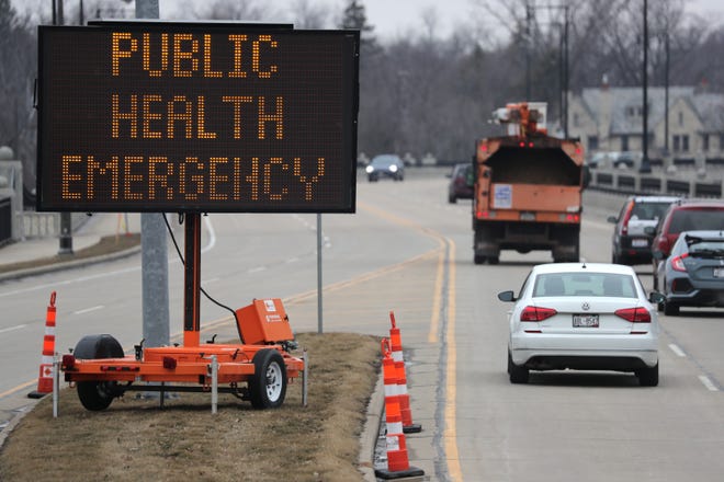 An emergency sign is posted on on the east side of the College Avenue bridge in Appleton, informing people of the coronavirus situation Wednesday.
