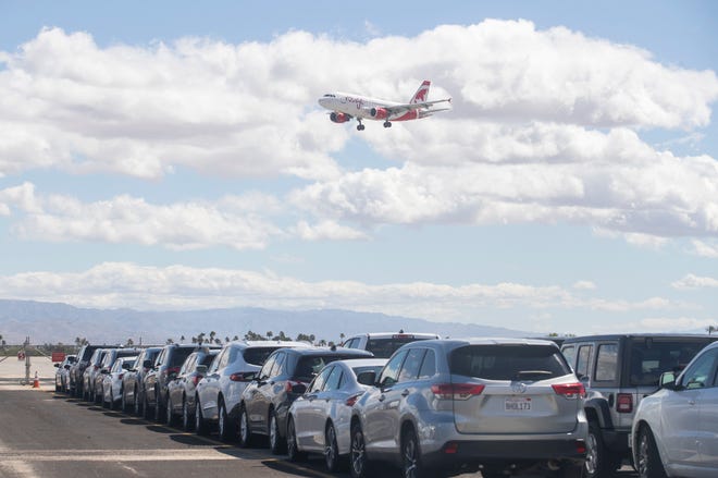 An airplane arrives at Palm Springs International Airport as rental cars are parked in a reservoir lot next to the landing strip on March 23, 2020. COVID-19 contingency has created a flood of unrented vehicles to sit flooding rental lots. 