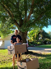 Vik Chhabra and his 7-year-old son Ethan before a box of food donated by neighbors for a micro-food drive Chhabra hosted in his driveway Tuesday, March 24, 2020, to help his church restock area food pantries.