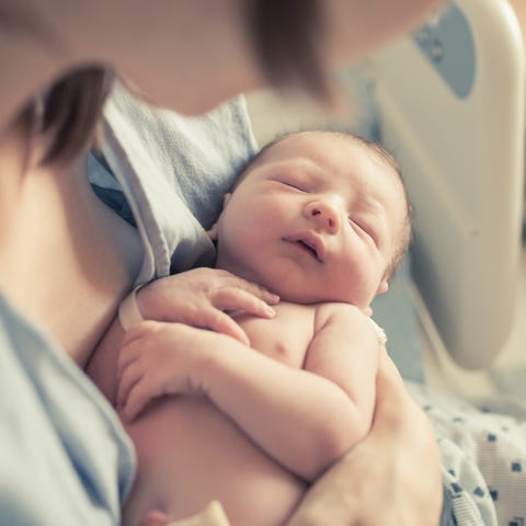New born baby boy resting in mothers arms.
