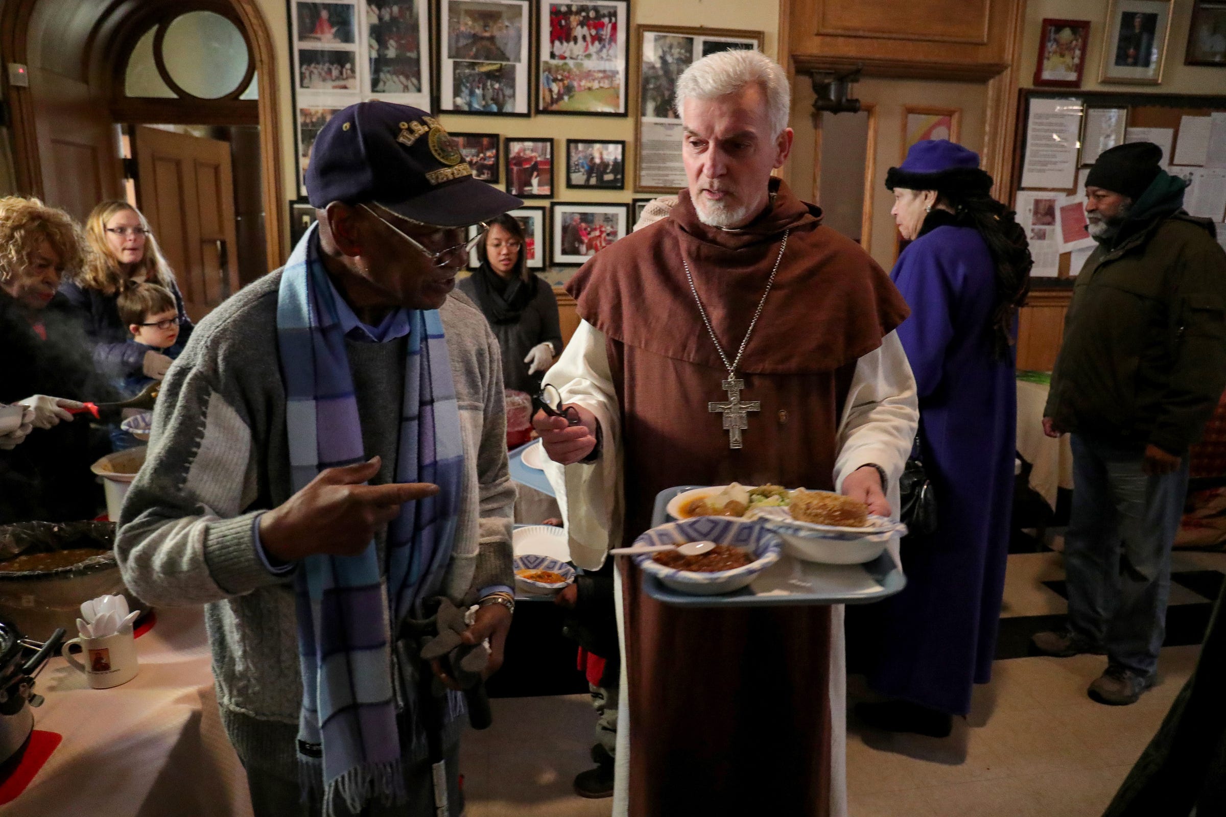 Bishop Karl Rodig helps Bobbie King a US Army vet to his table services at Cathedral of St. Anthony in Detroit Sunday, January 26, 2020.