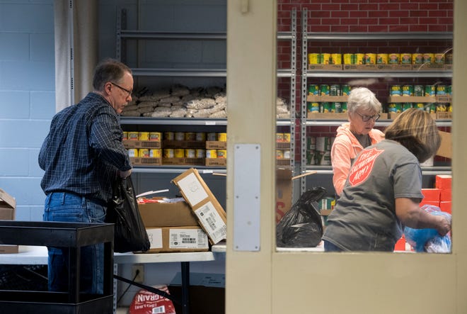 Volunteers Bill Fenet, left, Susan Wood, center, and Chris Kuryla, right, work in the food pantry at the Salvation Army in Evansville, Ind., Wednesday afternoon, March 25, 2020. The food pantry is open 1-3 p.m. Monday, Wednesday and Friday.