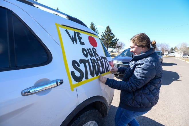 Mountain View Elementary School second grade teacher Brenna Norris tapes a sign to her car ahead of the Mountain View's teacher parade through the various neighborhoods the school serves.