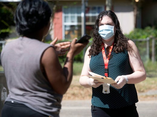 Children's Home Society representative Jennifer Carrancejie listens as a resident of the Pinecrest neighborhood asks how to connect with vital services amid the COVID-19 shutdown during a tour of the area on Thursday, March 26, 2020.