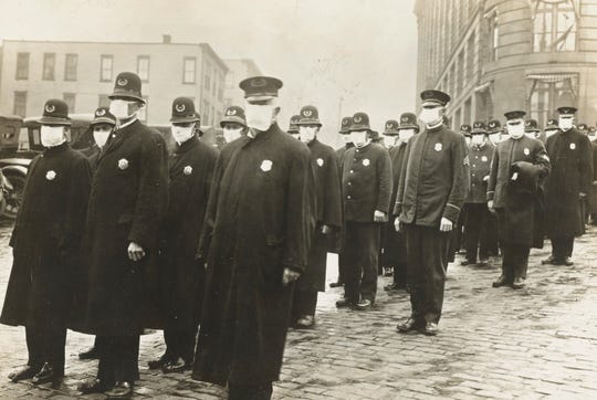 Seattle police officers wear masks during the influenza epidemic made by the local chapter of the American Red Cross in this National Archives photo dated December 1918.