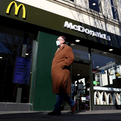 A man wearing a facemask walks past a McDonald's r