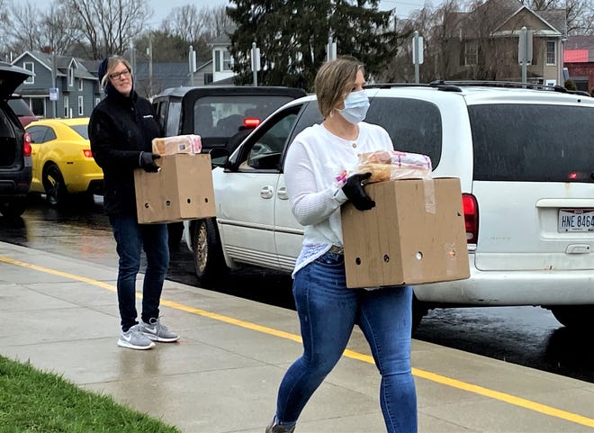 Nikki Williamson, right, carries a box of food to a family as Kristi Seymour waits for the next family at Mount Pleasant Elementary March 27. She was with a group of volunteers distributing food gathered and packed by Connexion West to help feed families during Lancaster City Schools' spring break and during the coronavirus pandemic.