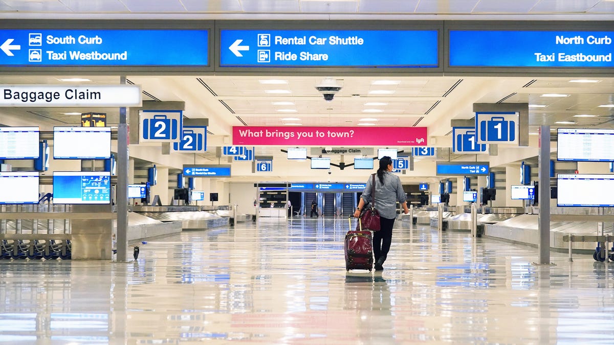 A lone traveler enters an empty baggage claim area in Terminal 4 at Sky Harbor International Airport in Phoenix. Airlines are reducing flights due to the coronavirus COVID-19 outbreak.